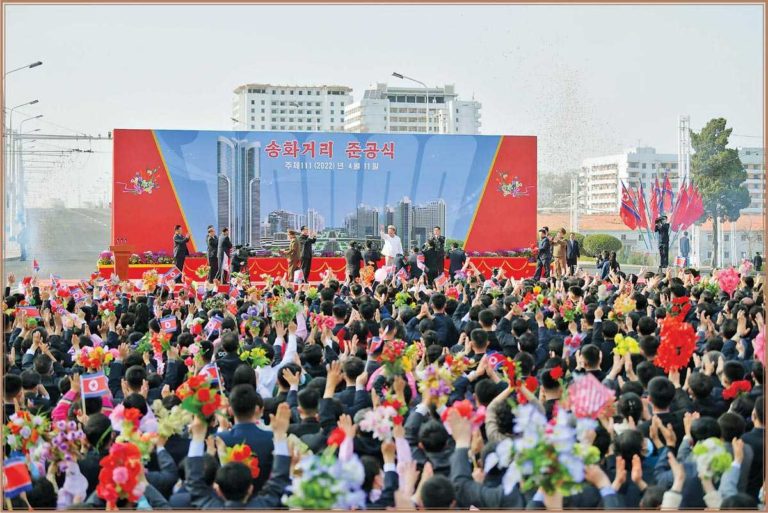 Kim Jong Un erwidert den begeisterten Jubel und beglückwünscht herzlich Werktätige, Herren der neuen Straße und neuer Wohnungen.